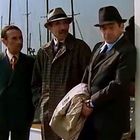 Drei Männer in Anzügen und Hüten stehen nebeneinander, teils an eine Wand gelehnt; im Hintergrund sieht man Schiffssegel.