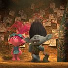 "RUN", "NO", "DANGER", "EAT US" in orange auf Wänden. Zwei bunte Figuren mit auffälligen Frisuren in einer Höhle.