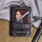 "Steelborn, Taylor J. LaRue" steht auf einem Buchcover mit einer Frau, die ein Schwert trägt und rote Haare hat.