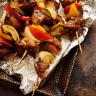 Gegrillte Fleischspieße mit Paprika und Zwiebeln auf einem Backblech mit Alufolie.