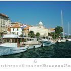 Text: "Sibenik", "6", "CASARES EDITION"
Szene: Boote am Wasser, historische Gebäude mit orangenen Dächern, Flaggen.