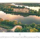 Text: "Festung Modlin" und darunter "6". Ein Fluss mit einer alten Ruine umgeben von vielen Bäumen.