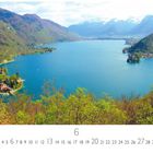 "Lac d'Annecy, Haute-Savoie" steht neben einem Kalender. Ein großer, klarer See, umgeben von grünen Bergen.