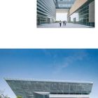 Moderne Architektur, klares Glas und Metall, horizontale Linien, Menschen gehen durch einen Durchgang, umgeben von Bäumen.