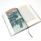 Textseite und Illustration eines Zuges und einer Menschenmenge im Schnee in einem aufgeschlagenen Buch mit Lesebändchen.