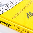 Gelbes Buchcover mit den Texten "Ferdinand von Schirach" und "Alexander". Illustration: Mensch auf einer Mauer sitzend, Wasserwellen.