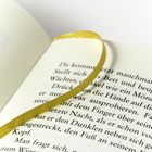 Text auf einer Buchseite, mit einem gelben Leseband. Klarer, schwarzer Druck auf weißem Papier.