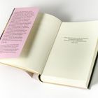 Ein aufgeschlagenes Buch mit einem Zitat von Homer aus der "Odyssee" auf der rechten Seite und rosa Textblatt links.