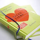 Auf grünen Buchcover steht "Ronja von Rönne", "ALLES LIEBE", "Roman". Ein rotes Herz und ein blaues Band zieren es.