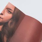 Kein Text erkennbar. Ein Magazin zeigt das Gesicht einer Frau zur Hälfte, daneben eine leere braune Seite.