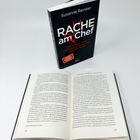 Das Buch "RACHE am Chef" von Susanne Reinker steht aufrecht. Ein weiteres Buch ist geöffnet, Seiten 106 und 107 sind sichtbar.