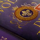 Text: "SPIEGEL Bestseller." Goldene, verzierte Schrift, ein lila Buchcover mit einem königlichen Emblem in der Mitte.