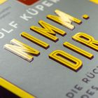 Text: "WOLF KÜPER NIMM DIR: DIE RÜCKEROBERUNG DES GUTEN". Grauer Hintergrund mit gelb-violetter Schrift. Buchcover.