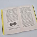 Ein Buch liegt offen, die Seiten 154 und 155 zeigen Text und zwei Münzen. Der Einband ist gelb.