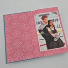 Texte: "46", "BR". Eine Illustration von zwei Personen auf einer Eisfläche. Hintergrund in Pink mit Eishockey-Sticks und Teddybären.