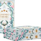 "Drowning Thrones: Egypt Empire." Illustration mit blauen Pflanzen und rosa Blumen, goldene Elemente und Sonnenmotiv.