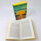 Ein Taschenbuch mit dem Titel "Kurt Prödel Klapper". Daneben liegt es geöffnet, die Seitenzahlen 146 und 147 sichtbar.