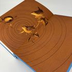 Brauner Hintergrund mit konzentrischen Kreisen, drei Vögel auf Zweigen, blaues Buchcover am Rand sichtbar.