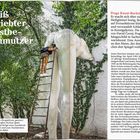 "Heiß geliebter Nestbeschmutzer." Eine Person steigt eine Leiter zu einer großen Statue hoch, umgeben von Bäumen.