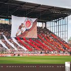 "Astra. Was dagegen?" in einer Stadionkulisse, mit Fans und großen Bannern. Kalenderblatt für Juni 2027 zeigt ein Fußballspiel.
