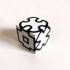 Ein weißer Würfel mit schwarzen, geometrischen Mustern, die an Puzzles erinnern.