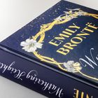 "Emily Brontë", "Wuthering Heights" auf blauem Hintergrund mit goldenen Verzierungen und weißen Blumen.