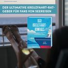 "DER ULTIMATIVE KREUZFAHRT-RATGEBER FÜR FANS VON SEEREISEN" steht über einem Buch mit einem Schiff, Beine sind hochgelegt.