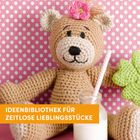 IDEENBIBLIOTHEK FÜR ZEITLOSE LIEBLINGSSTÜCKE. Ein gehäkelter Teddybär mit Blume und Klee vor rosa gepunktetem Hintergrund.