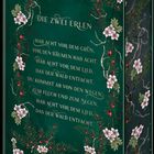 Das Cover zeigt goldene Schrift auf grünem Hintergrund: "DIE ZWEI ERLEN". Es ist verziert mit Blumen und roten Beeren.