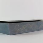 Ein dickes, dunkelblaues Buch mit einem eleganten, goldenen, geschwungenen Muster auf dem Buchschnitt.