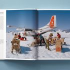 Ein Flugzeug steht im Schnee, umgeben von Männern, die Kisten mit der Aufschrift "Kellogg's Corn Flakes" und anderen Marken stapeln.