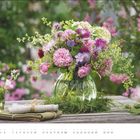 Text unten: "Juni". Ein bunter Blumenstrauß in einer Glasvase auf einem Holztisch im grünen Garten. Kalender darunter.