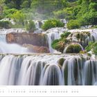 Text: "Juni" und "21.6. Sommersonntag". 

Mehrstufige Wasserfälle umgeben von üppigem Grün.