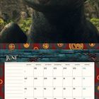 "Juni", Kalender mit Daten. Illustration von einem schwarzen Drachen mit großen grünen Augen, umgeben von Wald.
