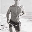 06 und ein Kalendarium mit Juni-Daten. Ein muskulöser Mann joggt am Strand entlang, im Hintergrund das Meer.