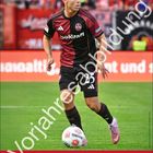 "Finn Becker. Vorjahresabbildung. Der Club. Juni. Fußballspieler in rotem und schwarzem Trikot auf dem Spielfeld."