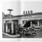 Text: "ESSO", "ESSO-WAGENPFLEGE", "L.LINN". Eine klassische Tankstelle mit Zapfsäulen und einem Auto, dessen Motorhaube offen ist.
