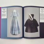 Linke Seite: "Girls' Ball Gown with Belt, 1797". Rechte Seite: "Girls’ Coat, 1981". Ein blaues Kleid und ein dunkler Mantel mit Kapuze.