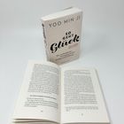 Ein Buch mit dem Titel "So geht Glück" von Yoo Min Ji steht aufrecht. Davor liegt es offen, Seite 120/121.