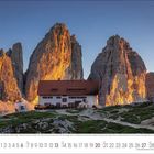 Kalender mit Zahlen und einem Foto von Bergen bei Sonnenuntergang. Eine Hütte steht im Vordergrund.