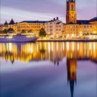 6, 2027, Datum: 1 bis 30. 

Eine Kirche am Wasser, umgeben von Gebäuden im Abendlicht, Spiegelung im Wasser. Kalenderblatt.