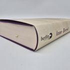 Text: "Anne Berest, berlin, 1989". Ein in hellem Umschlag verpacktes Buch liegt auf der Seite, lila Schnitt und Leseband.