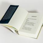 Ein aufgeschlagenes Buch zeigt das Inhaltsverzeichnis. Kapitelüberschriften und Seitenzahlen sind zu sehen. Ein dunkler Buchumschlag liegt daneben.