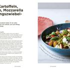 Salat-Rezept mit Kartoffeln, Nektarinen, Mozzarella. Foto: Bunter Salat in blauer Schüssel, Teller und Glas im Hintergrund.