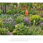 Juni. Ein üppiger, grüner Garten mit lilafarbenen Blüten und einem rotbraunen Krug, umgeben von natürlichen Zäunen.