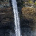 06 oben links mit einer Liste von Zahlen. Hoher Wasserfall, fällt in eine neblige, grüne Schlucht.