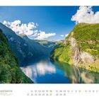 "Hurtigruten Geirangerfjord, 06. Landschaft mit grünen Bergen und klarem See unter blauem Himmel mit weißen Wolken."
