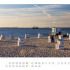 „Hörnum" steht auf einem Strandhäuschen. Strandkörbe auf dem Sand, Meer im Hintergrund, Schiff am Horizont.