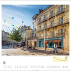 "Les Lunettes de François" ist an einem blauen Geschäft in einer sonnigen Straßenszene voller bunter Lampions zu sehen.