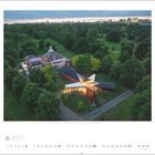 Logo © VOGELARTIST. Kalenderblatt Juni 2027 mit einem modernen Gebäude, umgeben von Bäumen und einer Stadtansicht im Hintergrund.